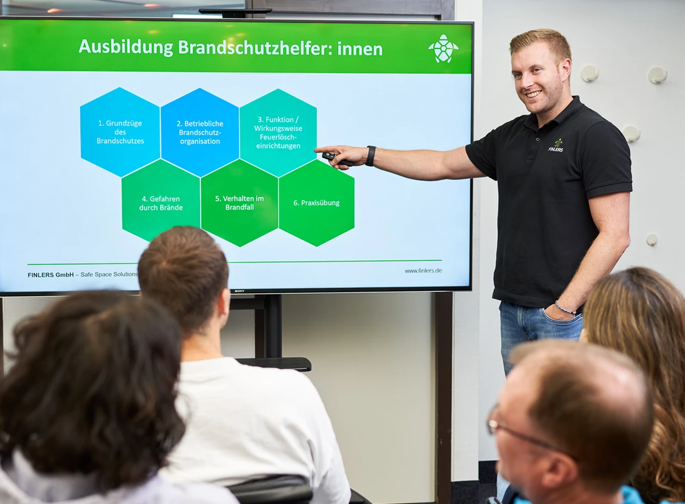 Ein FinLers Mitarbeiter unterweist am Whiteboard die Teilnehmer eines Brandschutzkurses